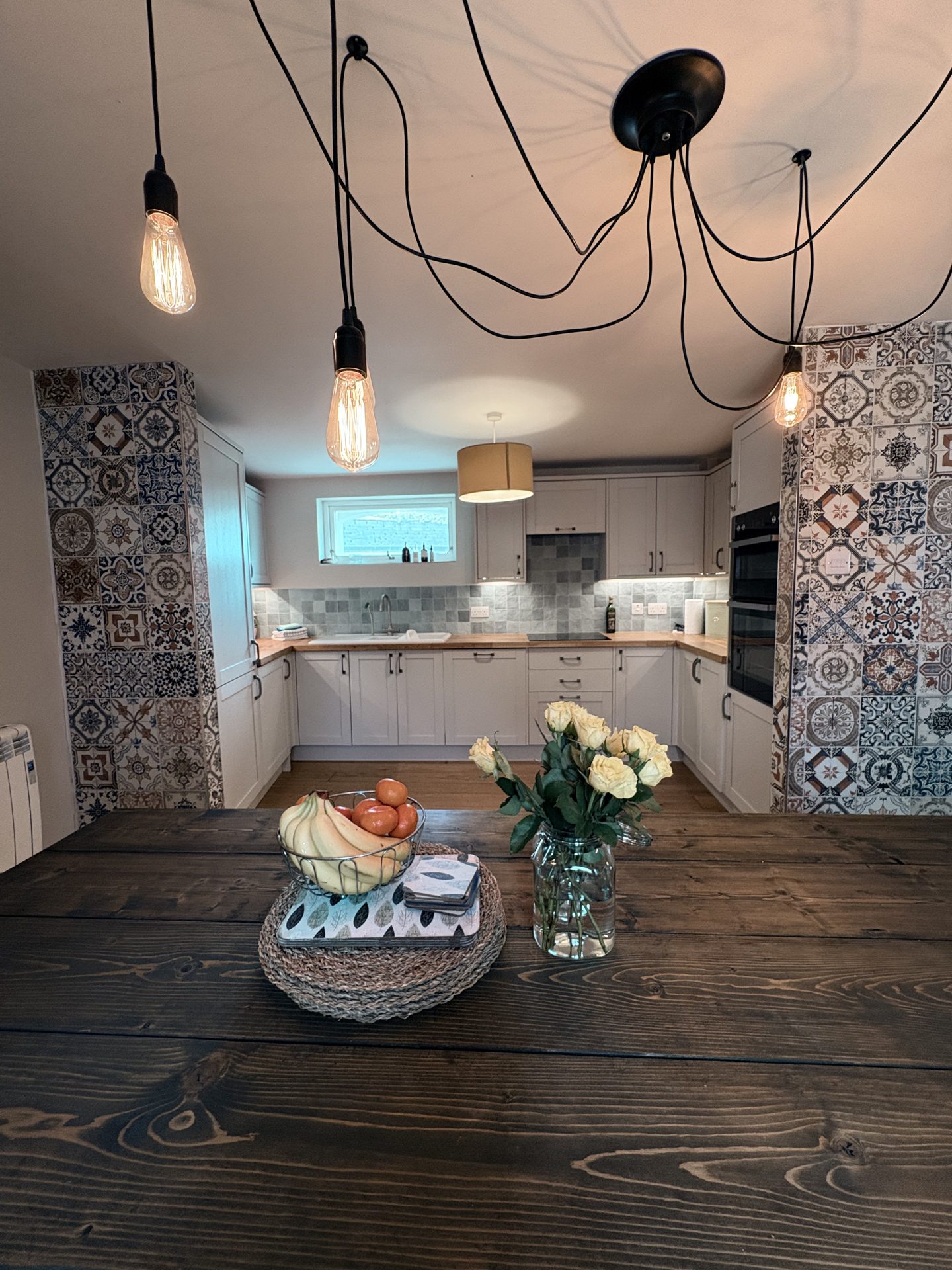 Well-equipped kitchen with patterned tiles and wooden dining table